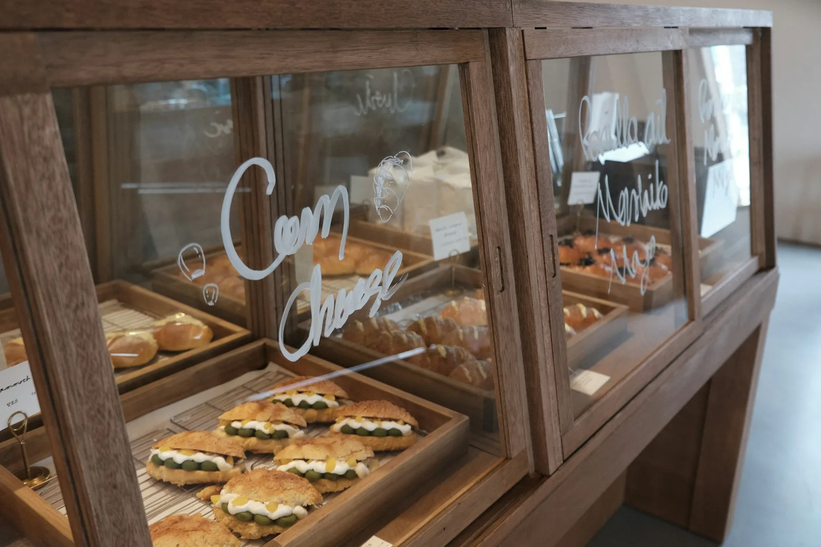 A wood-and-glass case of pastries with their names written on the glass in white pen.