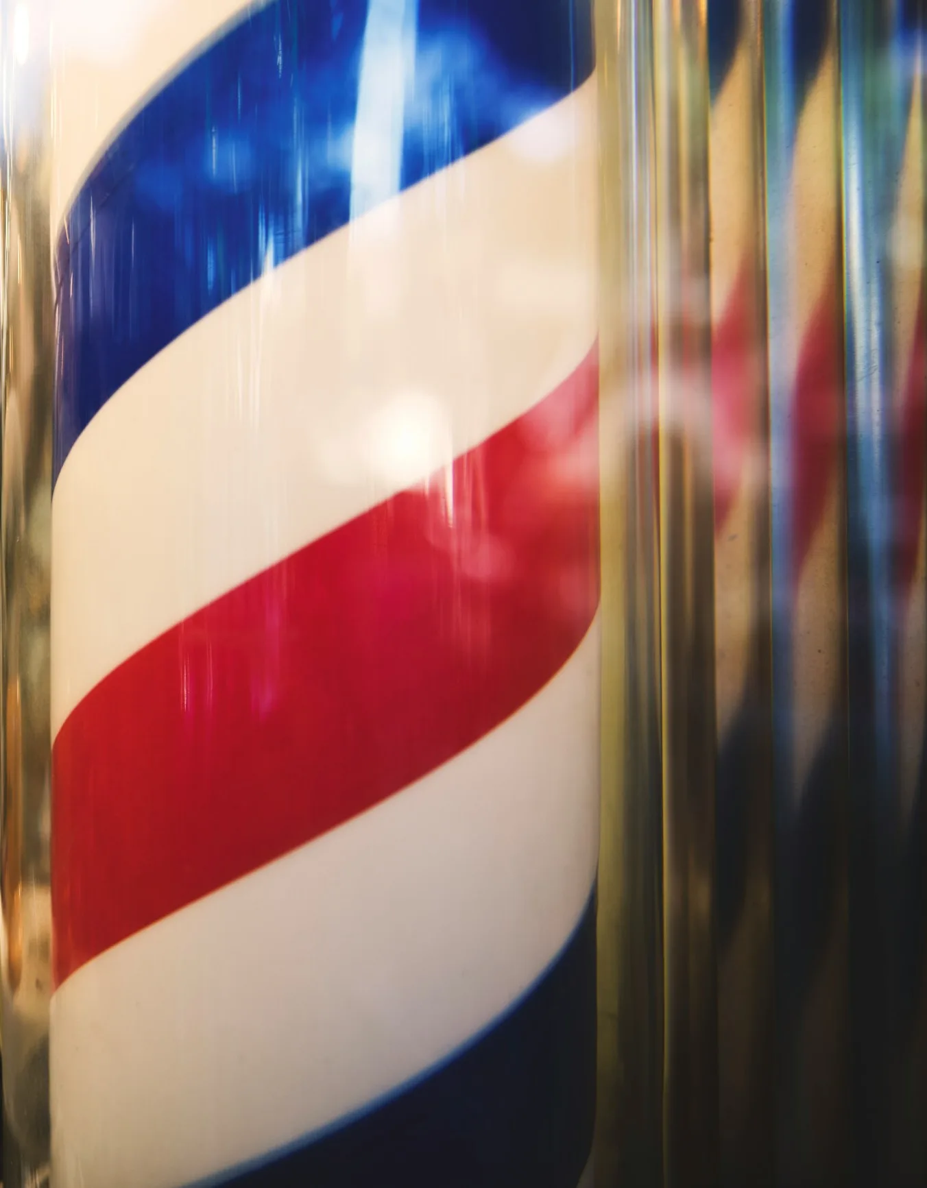 A red, white and blue barber pole, close up behind glass.