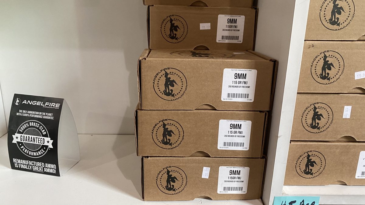 Stacked AngelFire boxes of 9mm ammunition on a store shelf with a guarantee card.