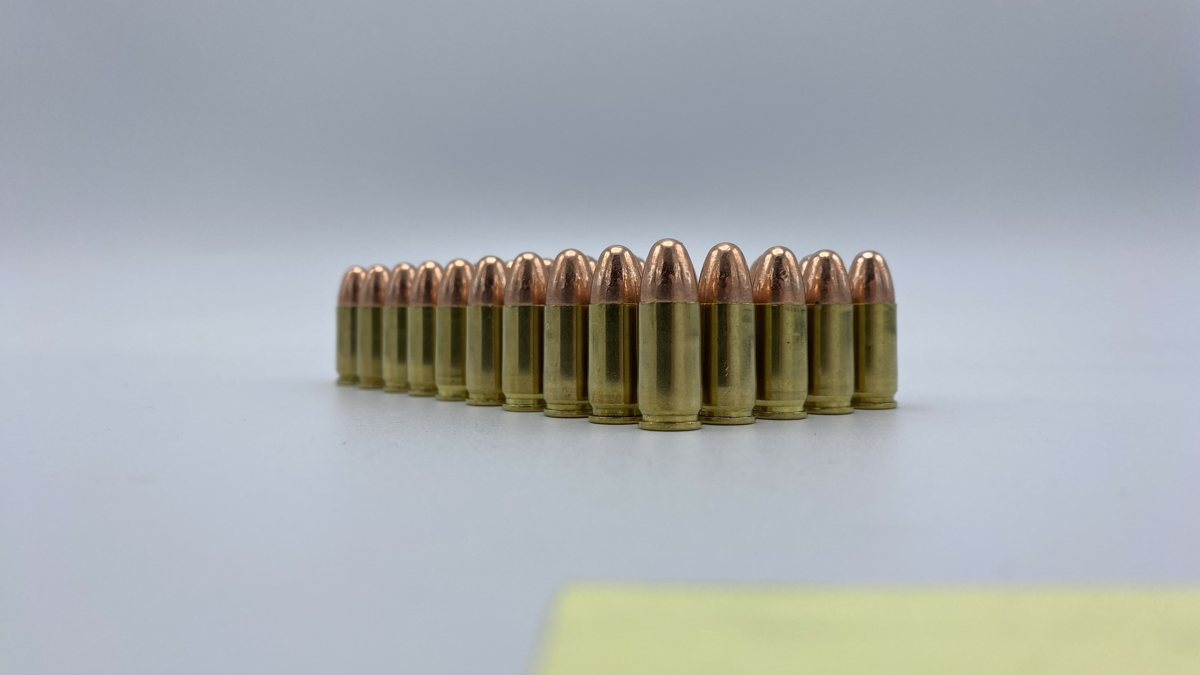 A row of 9mm full metal jacket rounds on a pale gray background.
